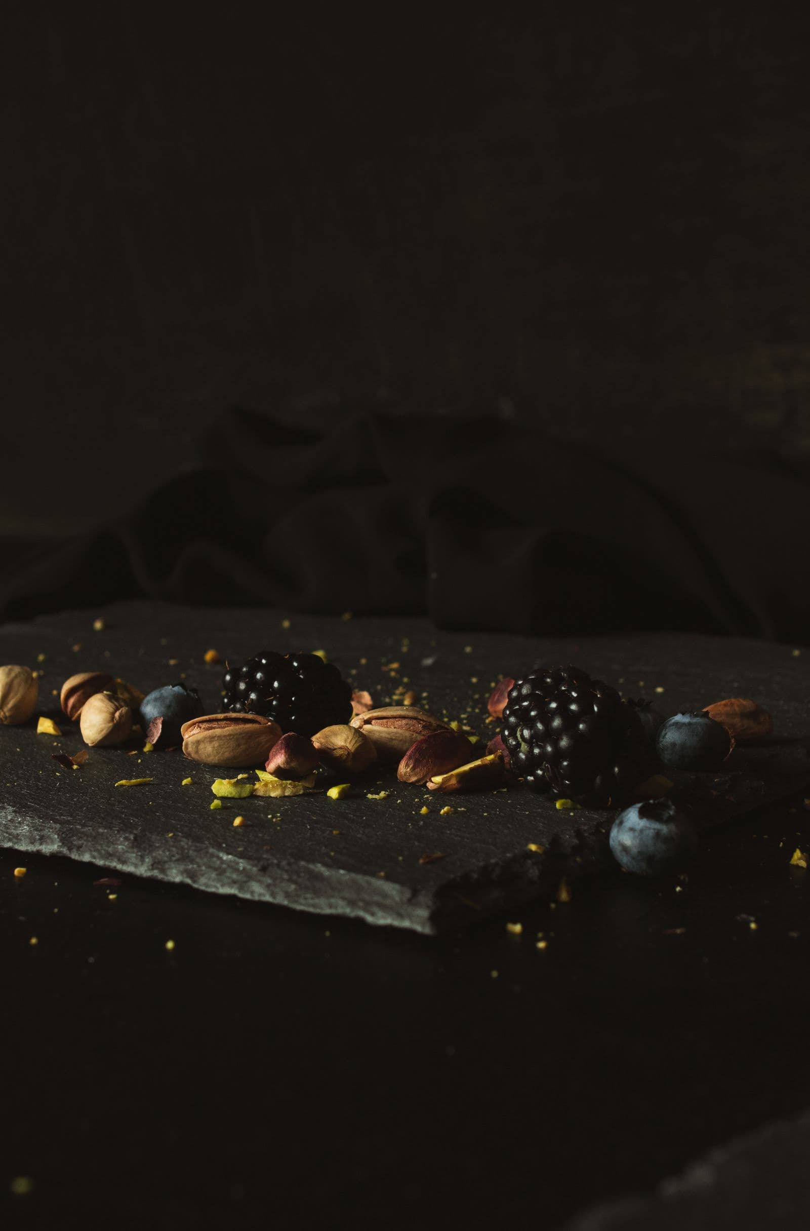 Blackberries, blueberries and pistachios on dark slate