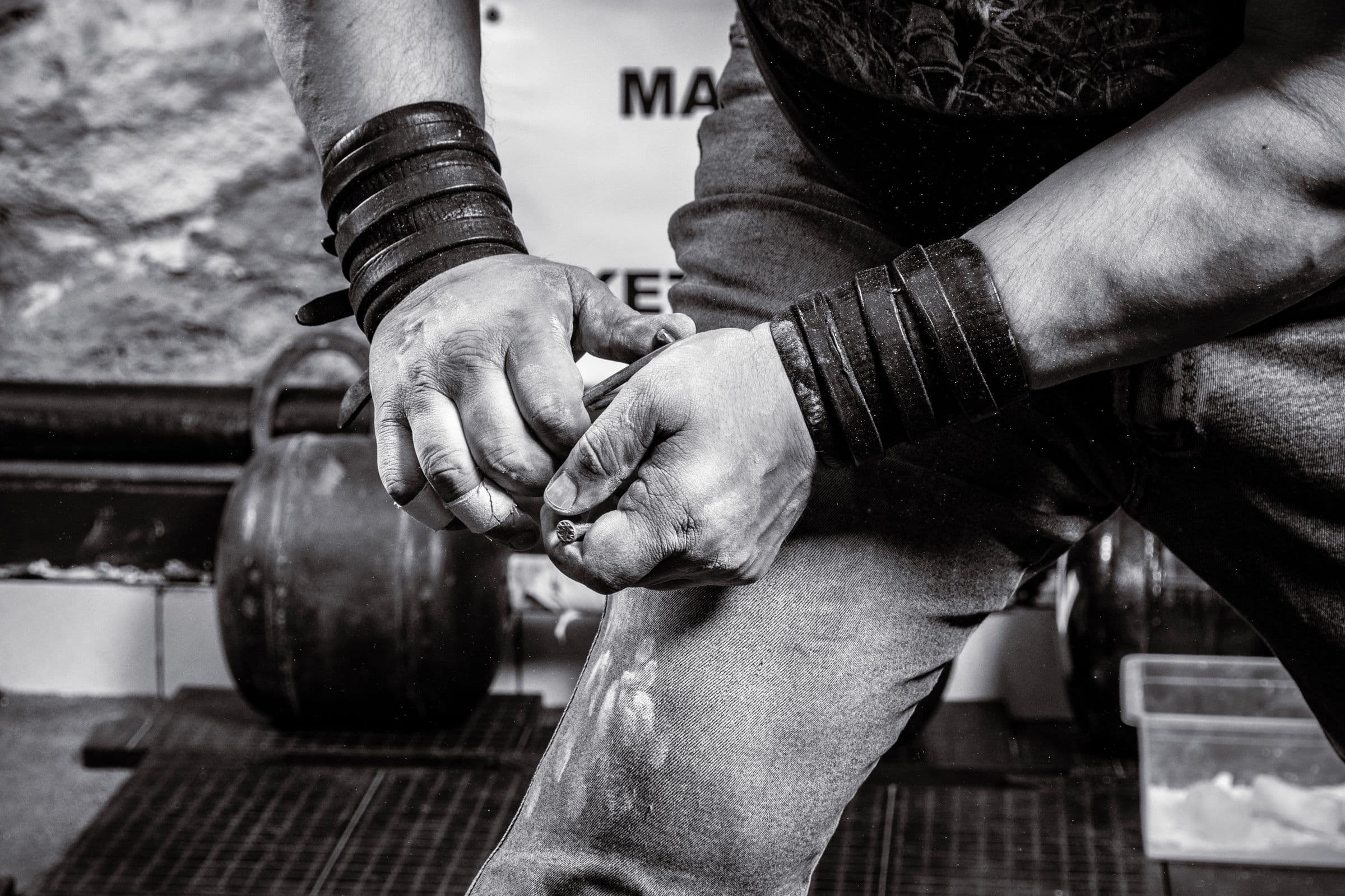 Close-up of chalked hands with leather wrist wraps, ready to lift